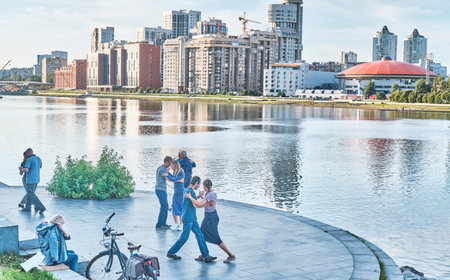 Adult couples dancing on embankment of Iset river over background of city buildings .のeditorial素材
