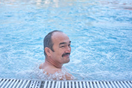 Smiling mature asian man in outdoor thermal pool with hydromassage.の写真素材