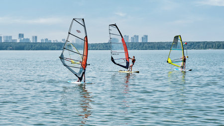 Windsurfing training. Several children floating on boards with sail on lakeのeditorial素材