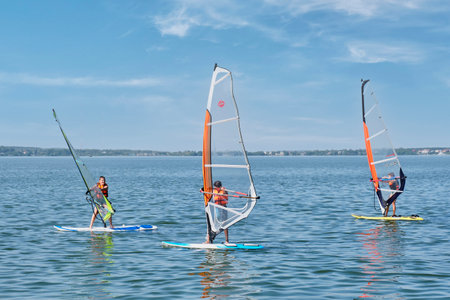 Windsurfing training. Children floating on boards with sail on lakeのeditorial素材