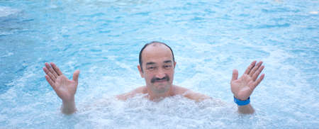 Mature asian man in outdoor thermal pool with hydromassage.