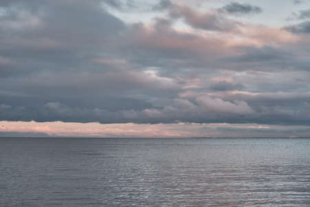 Beautiful dramatic cloudy sky over sea bay at sunsetの写真素材
