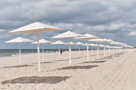 Baltic sandy beach with white wooden sun umbrellas in autumn. Seaside landscapeの写真素材