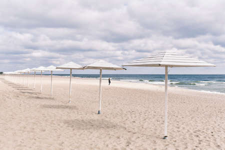 Baltic sandy beach with white wooden sun umbrellas in autumn. Seaside landscapeの写真素材