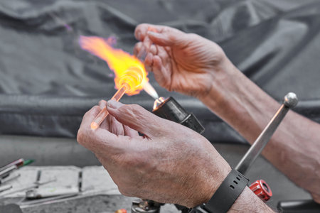 Process of artistic glass processing by burner flame. Hands of mature glassblowerの写真素材