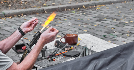 Process of artistic glass processing by burner flame. Hands of mature glassblowerの写真素材