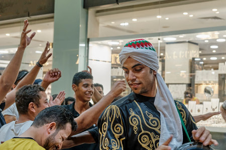 Portrait of young Egyptian in traditional clothes playing tambourine on street in evening.のeditorial素材