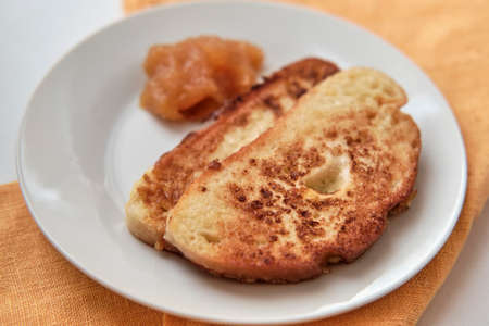 Two slices of white loaf fried with egg and apricot jam on white plate. Breakfast conceptの写真素材