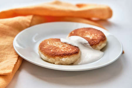 Two cheesecakes with sour cream on a white plate. Breakfast concept.の写真素材