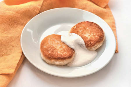 Two cheesecakes with sour cream on a white plate. Breakfast concept.の写真素材
