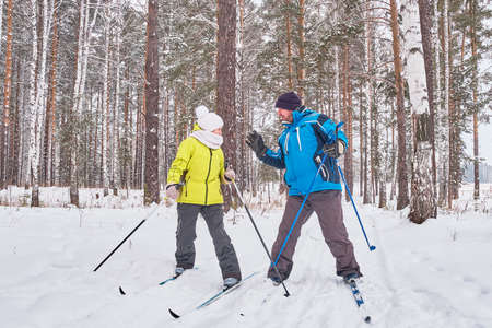 Quarrel of mature couple in winter sportswear are cross-country skiing in snowy forest.の写真素材