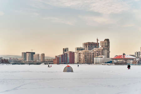 Winter cityscape of Yekaterinburg, Russia. Ice of city pond covered in snow, fishermans tent.の写真素材