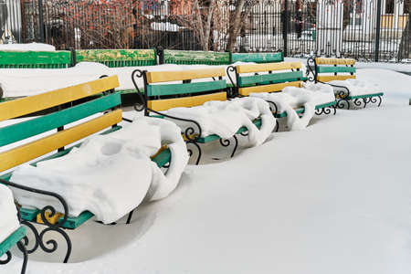Snow-covered wooden benches in summer amphitheater of city park.の写真素材