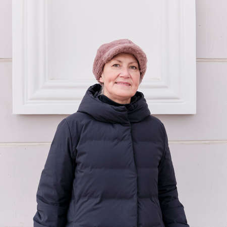 Winter portrait of smiling senior woman looking at camera, wearing faux pink fur cap.の写真素材
