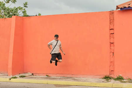 Mature Asian man in casual clothes jumping on background of bright orange wall.の写真素材