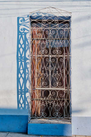 Typical window of building with wrought iron curly grille in old colonial city of Trinidad, Cuba.の写真素材