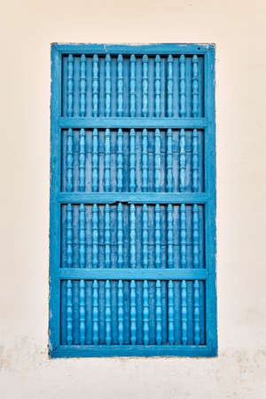 Closed window with typical blue wooden bars in beige building in old colonial city of Trinidad,Cubaの写真素材