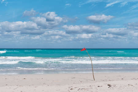 Red flag on sandy beach of Atlantic Ocean, Varadero, Cuba. Danger sign, swimming is prohibited.の写真素材