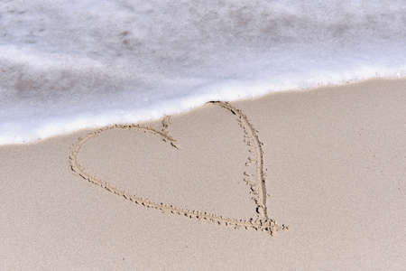 Contour of heart drawn on white sand of tropical beach.の写真素材