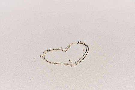 Contour of small heart drawn on white sand of tropical beach.の写真素材