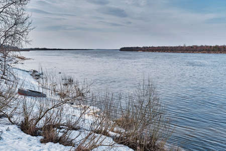 Spring landscape on river, Russia. Melted snow, small pieces of ice floating in water.