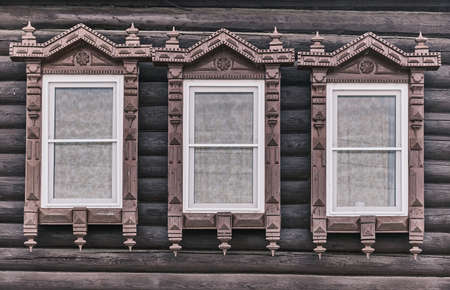 Wndows with carved wooden architraves. Log facade of typical rural Russian house.の写真素材