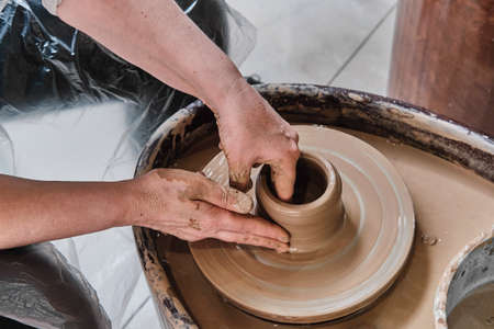 Hands of senior woman sculpting clay vase on potters wheel.の写真素材