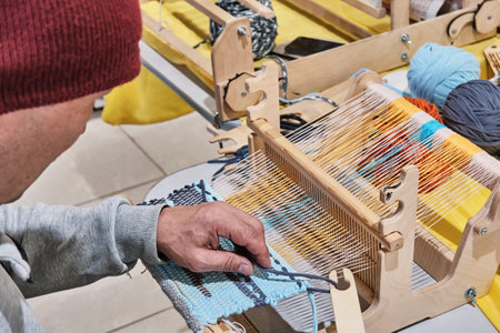 Hand of older man, who weaving small rug with pattern on wooden manual table loom.の写真素材