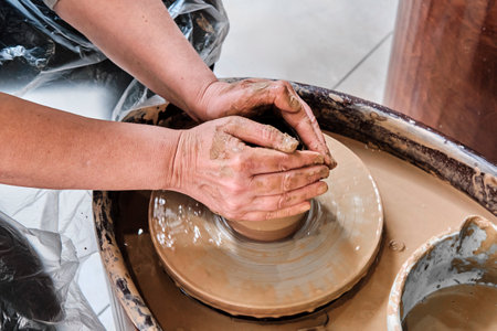 Hands of older woman sculpting clay vase on potters wheel.の写真素材