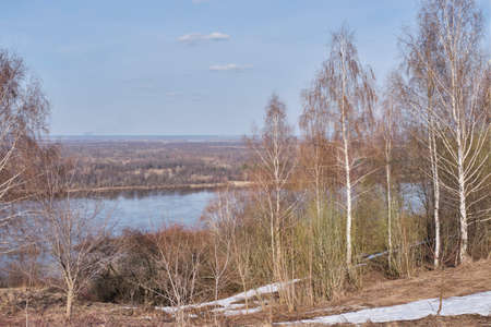 Spring landscape. View of river from hill. Bare trees, snow still lying in hollowsの写真素材