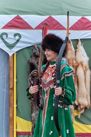 Asian woman in traditional festive Bashkir clothes with bow and arrow at Sabantuy folk festival.のeditorial素材