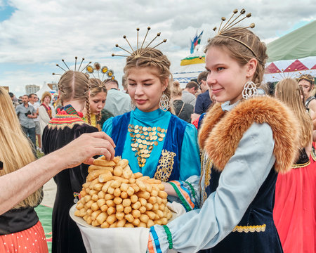 Girls in national festive clothes treating Bashkir dessert at the Sabantuy holidayのeditorial素材