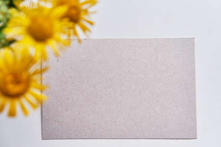 Greeting mockup scene on white table. Blank paper, bouquet of yellow wild meadow flowers defocusedの写真素材