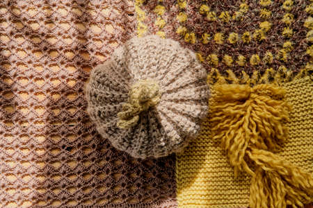 Knitted beige wool pumpkin on table covered with knitted patchwork tablecloth. Top viewの写真素材