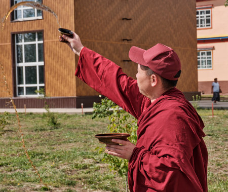 Buddhist monk in burgundy clothes performs ritual. Ivolginsky Datsan, Buryatia. Russia.のeditorial素材