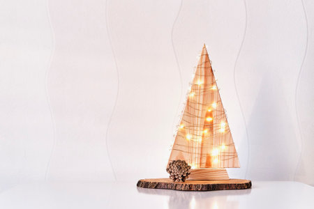 Christmas interior decor.Wooden stylized Christmas tree with lighted garland,pine cone,on tree cutの写真素材