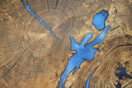 Saw or cut of solid section of natural wood with inserts of blue vegetable epoxy resin as abstract...