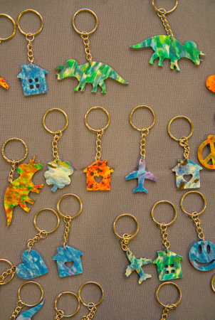 Colorful keychains made of multicolored recycled plastic caps on brown textile background. flat lay. top view.の写真素材