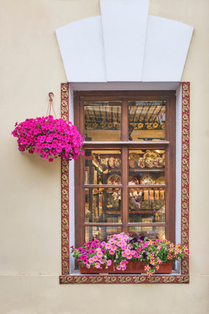 Wndow of souvenir shop, decorated with flowers in pots, framed with decorative wooden planks with floral pattern carved from wood. Facade of old tatar house in Kazan, Russiaの写真素材