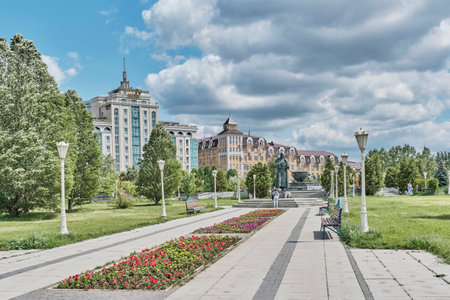 Kazan, Russia - June 8. 2023: View of the main alley of Millennium Park with a monument , a fountain , flower beds, benches, lampposts. Summer cityscape. travel conceptのeditorial素材