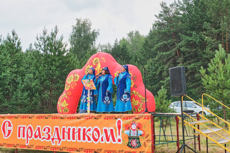 Aromashevo, Russia - June 15, 2023: Three mature women in stylized traditional ethnic tatar clothes performing on stage. Village festival takes place, Day of small motherland.のeditorial素材