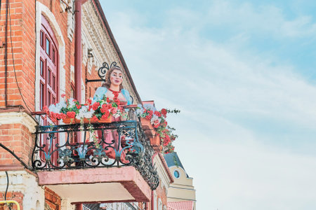 Kazan, Russia - June 15, 2023: Advertising street sculpture in decoration of restaurant, cafe. Growth figure of young woman standing among flowers on balcony and inviting everyone to enterのeditorial素材