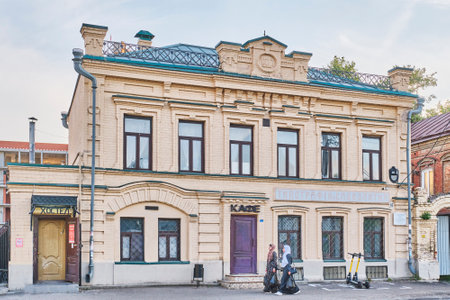 Kazan, Russia - June 15, 2023: Building of Millyat Printing House, 1908. Monument of residential architecture in eclectic style. Two girls in Muslim clothes with bags walking down street.のeditorial素材