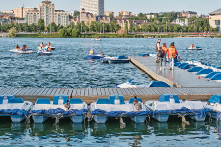 Kazan, Russia - June 17, 2023: Boat station on Lake Nizhny Kaban in downtown. People riding pedal boats. Active leisure. Summer city landscape.のeditorial素材
