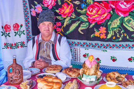 Irbit, Russia - August 11, 2023: Senior man in Armenian national clothes sitting at festive table...