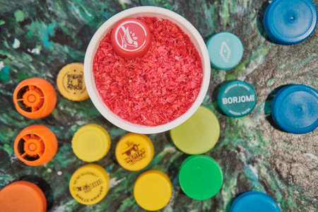 Yekaterinburg, Russia - April 22, 2023: Red shavings from plastic lids. Used to make various products from recycled material. Top viewのeditorial素材