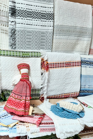 Homespun tablecloths and napkins with pattern in Russian style, crocheted things. Small slavic rag doll, amulet associated with pagan. Handmade souvenirs and gifts at market.の写真素材