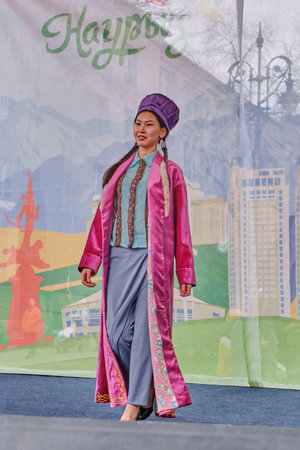 Almaty, Kazakhstan - March 21, 2024: Cute asian woman showing Kazakh designer clothes and accessories at fashion show during celebration of spring holiday of Nowruz on Zhibek Zholy streetのeditorial素材