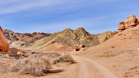 Road among colored sand hills over background of blue sky in Charyn Canyon National Park in...