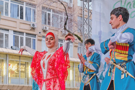 Almaty, Kazakhstan - March 21, 2024: Cute young girl and two boys in national traditional colorful clothes dance Caucasian dance during celebration of spring holiday Nowruz.のeditorial素材